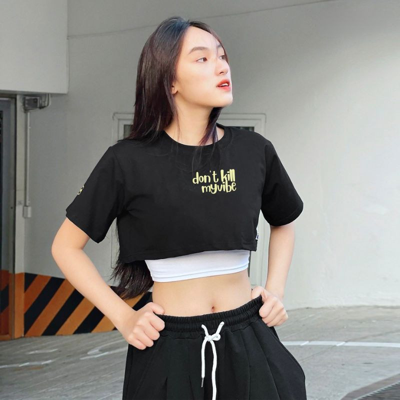 Cô gái cá tính với áo croptop form rộng màu trắng xám, phối layer cùng áo bra đen, tạo nên phong cách đường phố năng động và hiện đại