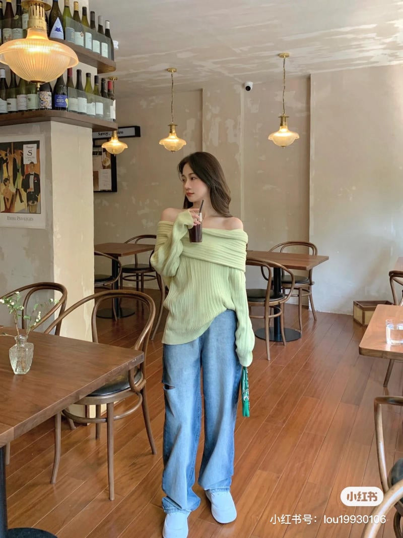 Cô gái mặc áo len trễ vai màu xanh bơ và quần jean rách gối