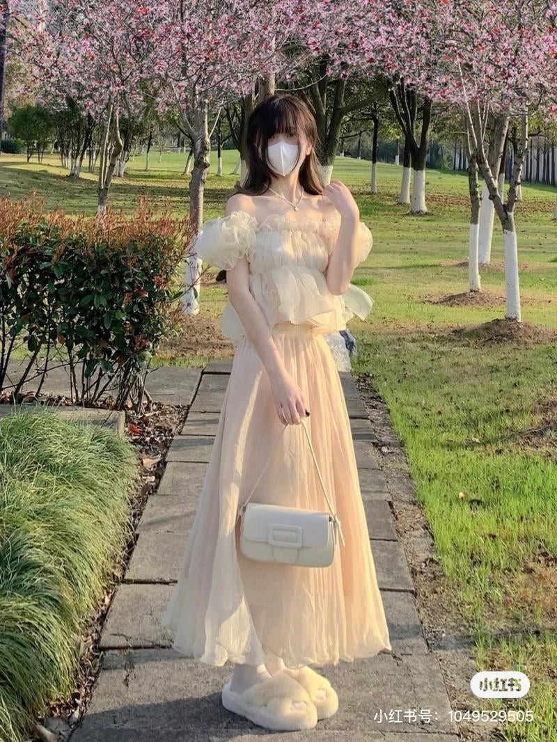 Cô gái mặc áo trễ vai croptop trắng và chân váy tutu voan màu be, tạo outfit tinh khôi