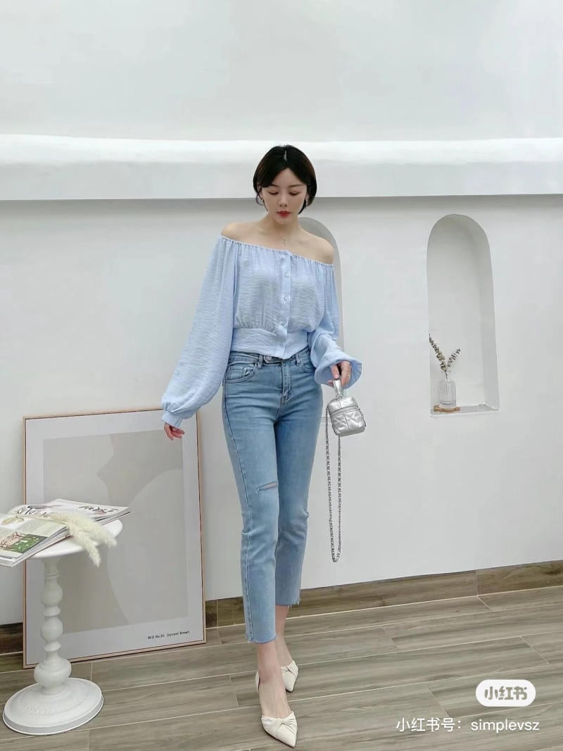 Cô gái tạo dáng tự tin với áo sơ mi trễ vai màu xanh nhạt và quần skinny jeans