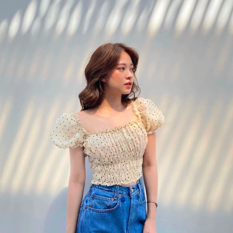 Mẫu áo croptop tay phồng màu trắng phối với quần denim, tạo phong cách vừa điệu đà vừa năng động cho chuyến đi biển