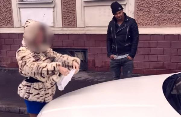 Ba cô gái trẻ mặc đồ lót, đang cúi người lau chiếc Mercedes màu đen giữa đường phố Moscow, khung cảnh đường phố và cây xanh làm nền.