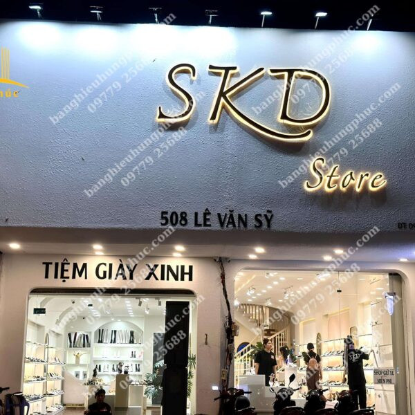 Biển hiệu cửa hàng thời trang nữ với chữ nổi màu vàng sang trọng trên nền tối