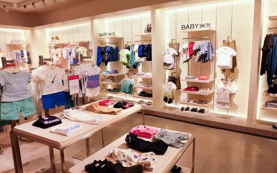 Mẫu nội thất shop quần áo trẻ em tạo cảm giác rộng rãi, thoáng đãng với tông trắng và gỗ sáng