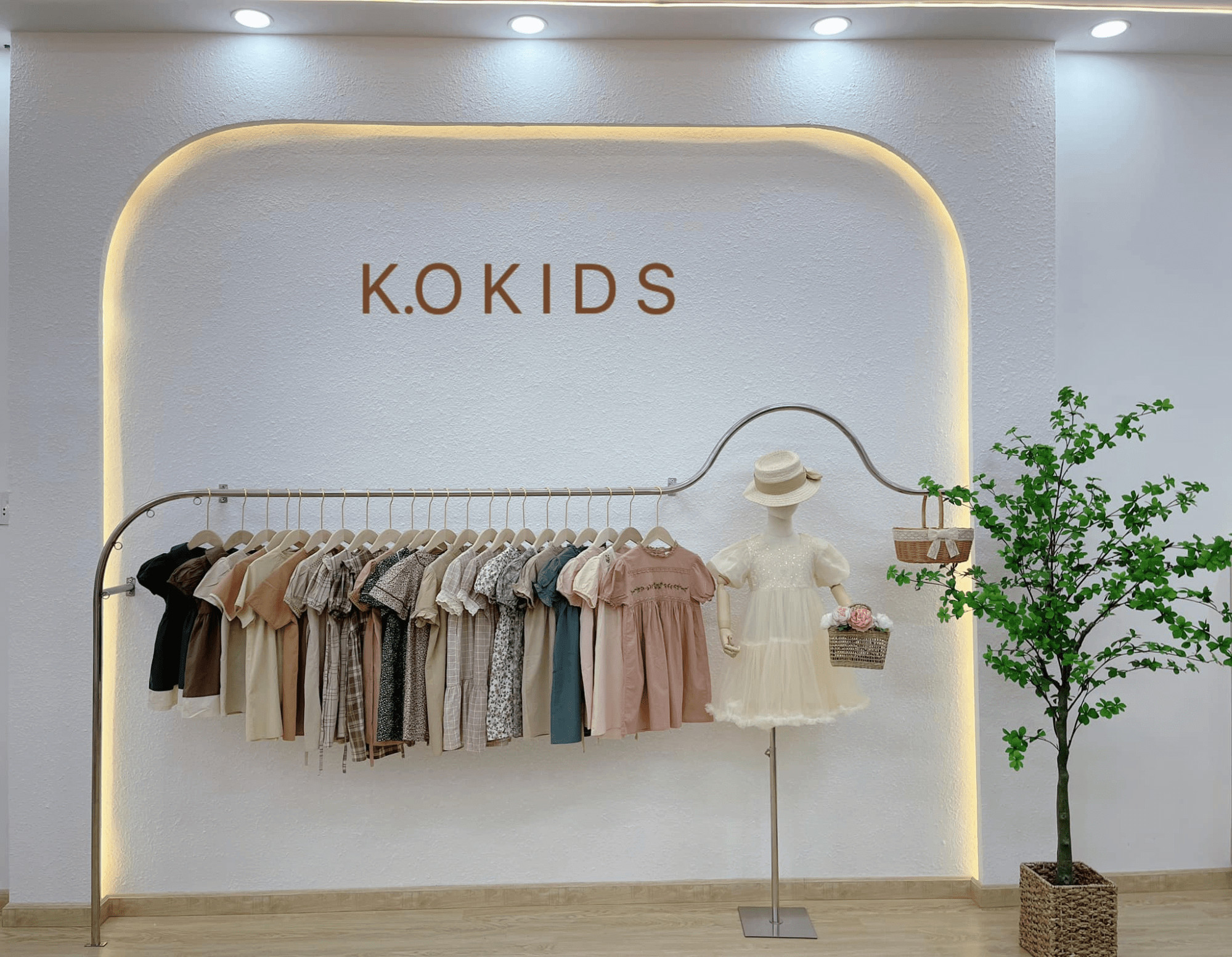 Mẫu shop quần áo trẻ em đơn giản nhưng tinh tế với nội thất gỗ sáng và tường trắng