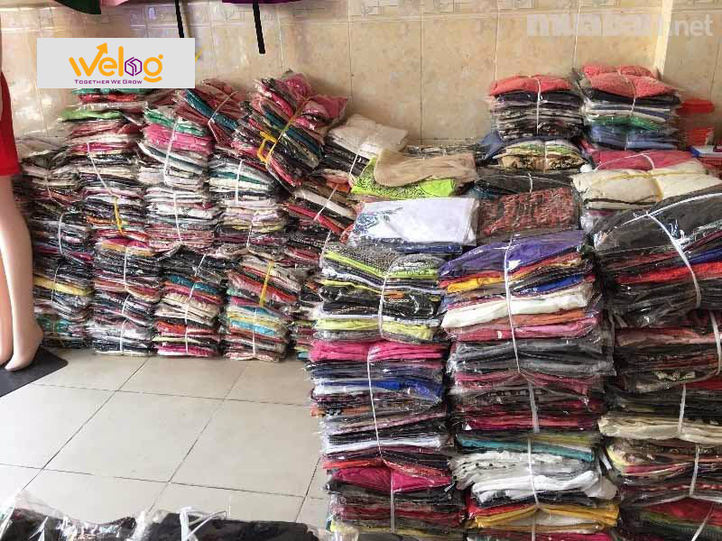 Một chồng quần áo bán sỉ với nhiều màu sắc và kích cỡ khác nhau, minh họa khái niệm "1 ri quần áo"