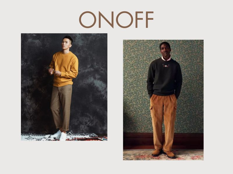 Người đàn ông mặc quần tây nâu, áo sweater màu be nhạt, giày sneakers trắng, tạo vẻ trẻ trung và năng động