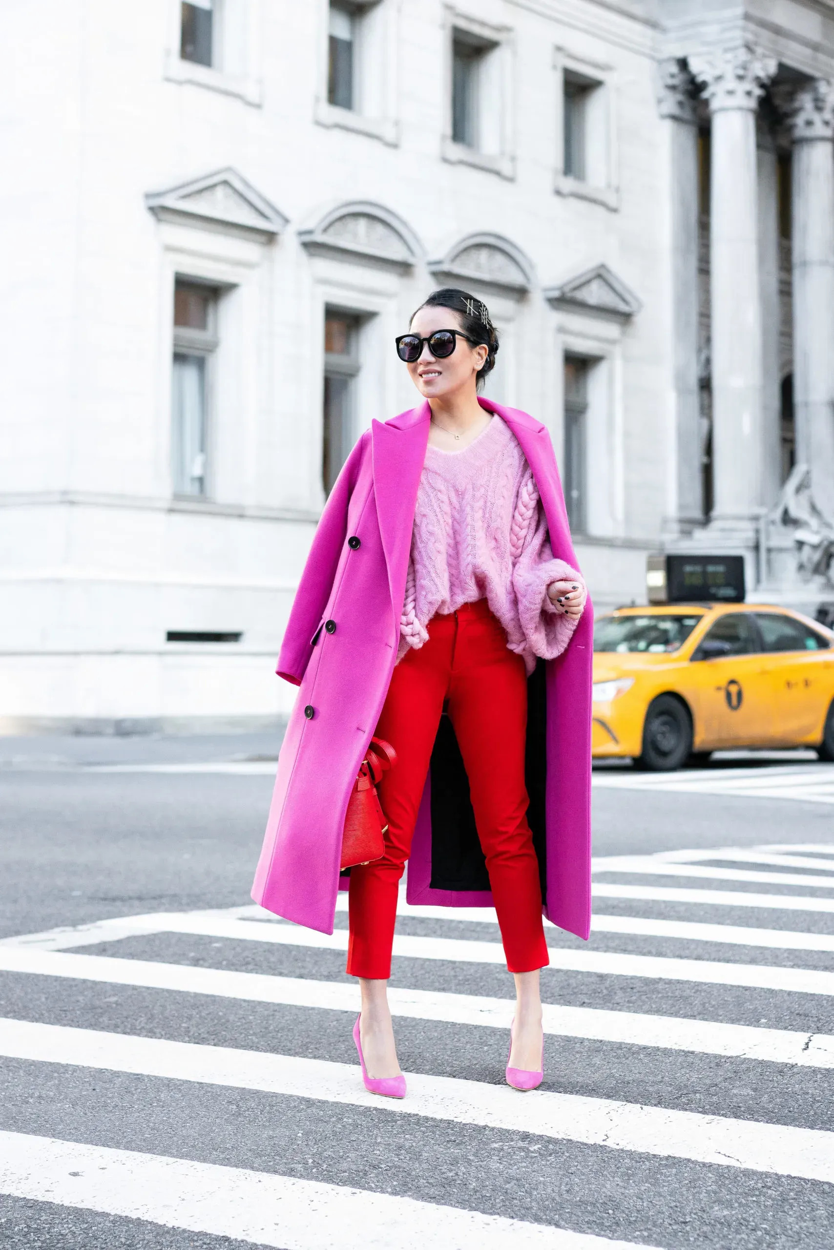 Quần âu hồng fuchsia nổi bật khi kết hợp với áo blazer đỏ đô và áo lụa cam đất, thể hiện sự phá cách và gu thời trang ấn tượng.