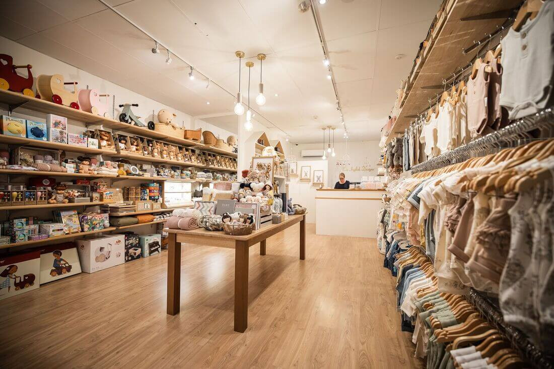 Thiết kế mẫu shop quần áo trẻ em nhỏ gọn, sử dụng tủ kệ màu trắng và hồng pastel