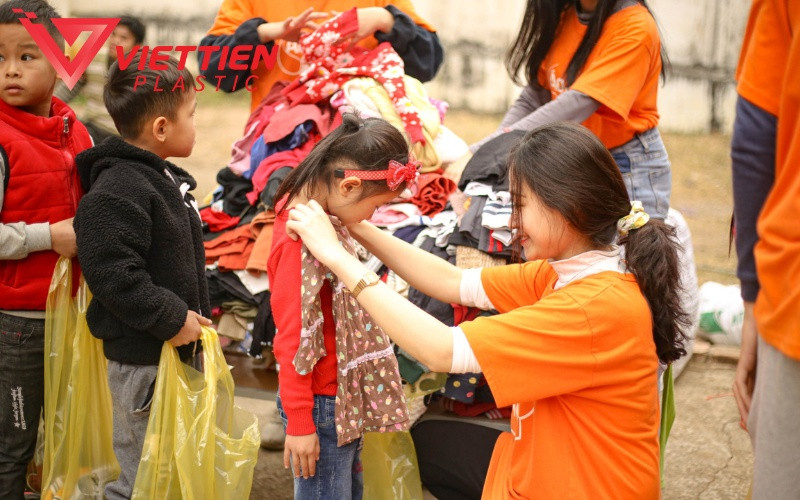 Bàn tay đang giữ một chồng quần áo cũ sạch sẽ, minh họa những lợi ích tích cực từ việc xử lý quần áo cũ đúng cách và bền vững.