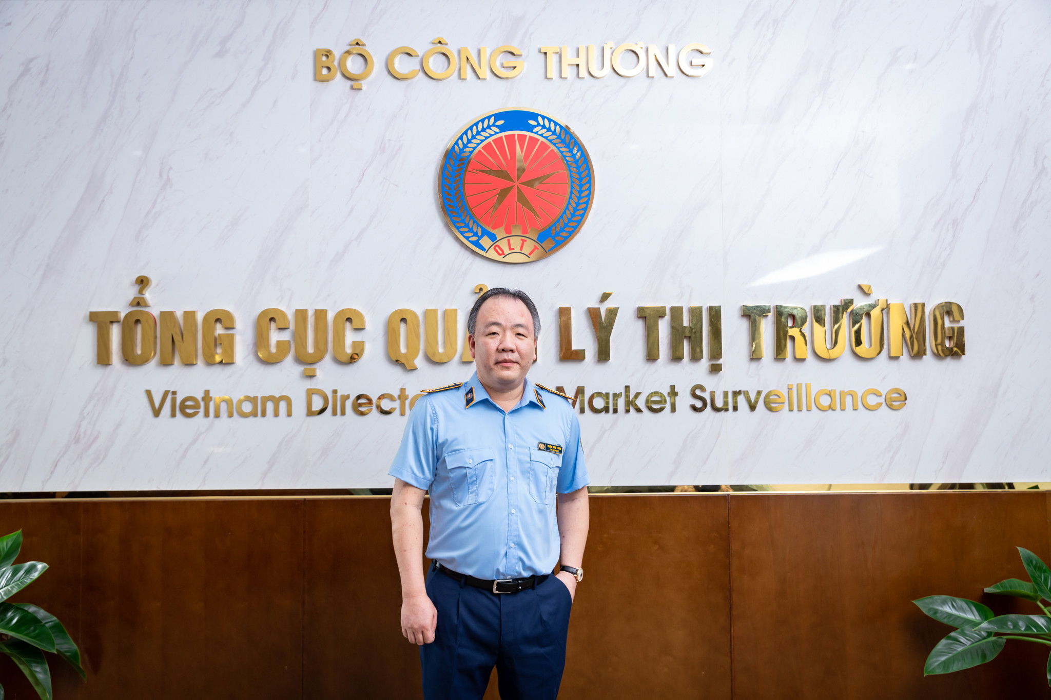 Cán bộ quản lý thị trường với nụ cười thân thiện trong đồng phục ngành, thể hiện sự gần gũi và chuyên nghiệp