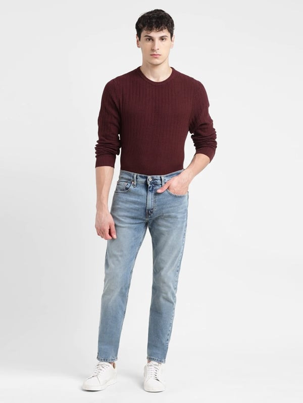 Chàng trai sành điệu với áo sweater đỏ đậm và quần jean xanh rách nhẹ