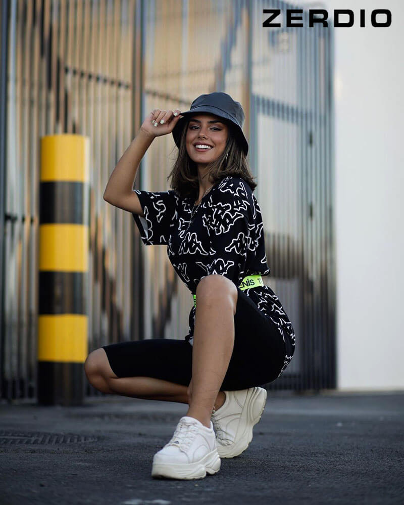 Cô gái trẻ năng động với mũ bucket đen, áo thun trắng và quần jeans xanh, tạo nên outfit hiphop nữ đơn giản nhưng sành điệu.