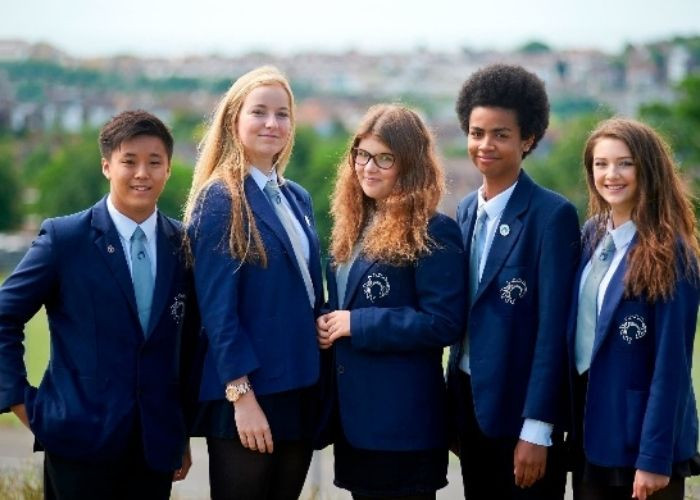 Học sinh Anh Quốc trong bộ đồng phục quần tây áo trắng truyền thống, kết hợp cà vạt sọc và chân váy chữ A