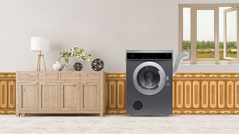 Máy sấy quần áo thông hơi màu trắng với cửa tròn mở, được đặt trong không gian hiện đại