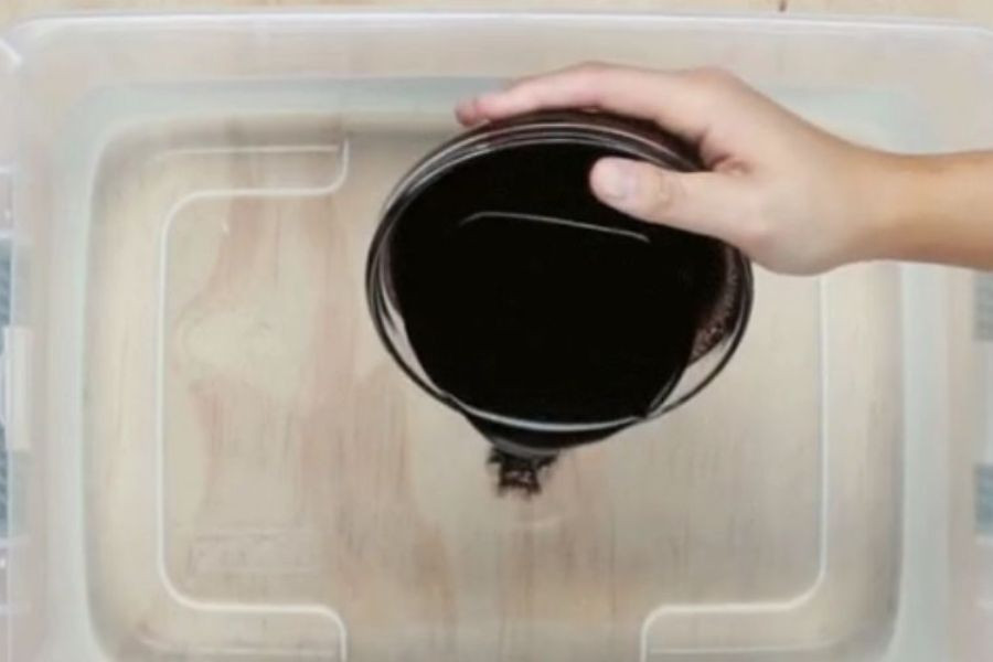 Một chiếc áo trắng đang được ngâm trong dung dịch nhuộm màu xanh, minh họa cách nhuộm quần áo màu xanh dương bằng màu thực phẩm hoặc mực một cách đơn giản.