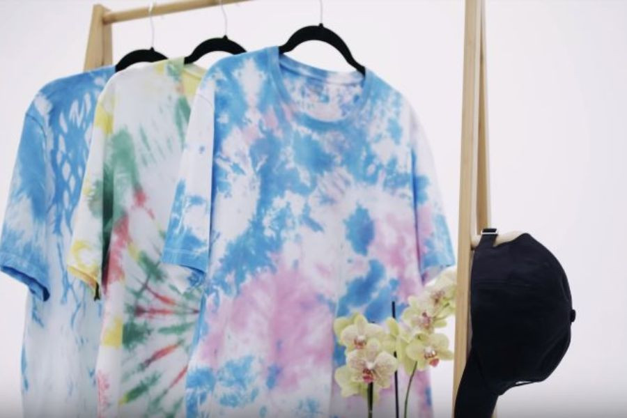 Người phụ nữ đang kiểm tra chất liệu vải áo phông trước khi tiến hành nhuộm, nhấn mạnh việc chọn đúng loại vải cotton hoặc lụa để nhuộm quần áo màu xanh dương tại nhà đạt hiệu quả tốt nhất.