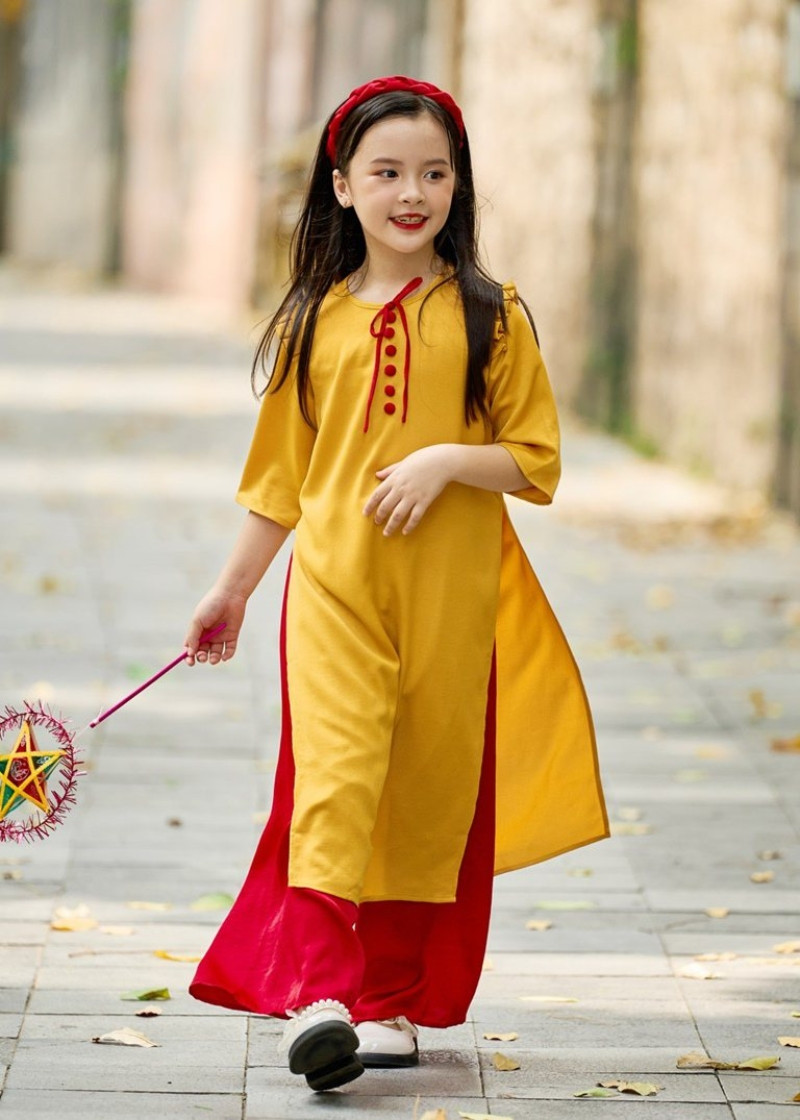 Người phụ nữ duyên dáng với áo dài cách tân màu vàng tươi phối quần đỏ, biểu tượng của sự may mắn và tài lộc dịp Tết