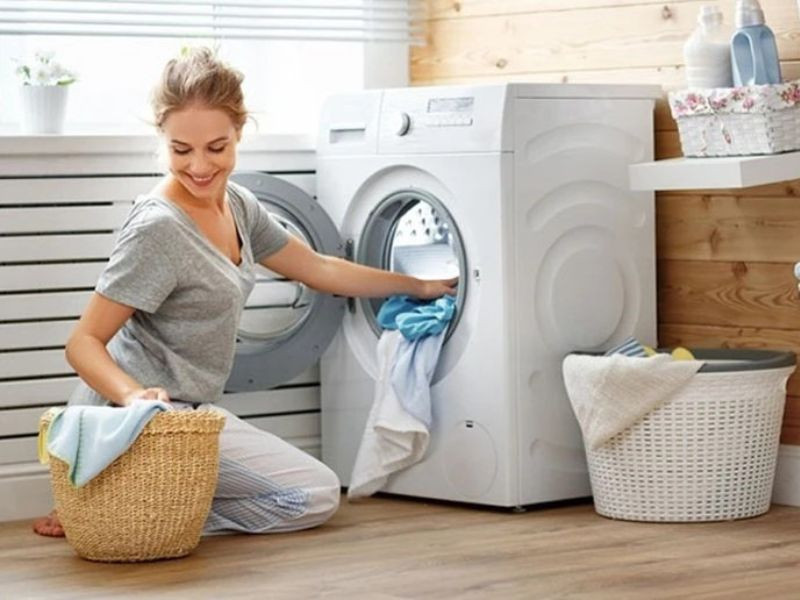 Người phụ nữ giặt quần áo trong máy giặt lồng đứng để ngăn ngừa nấm mốc