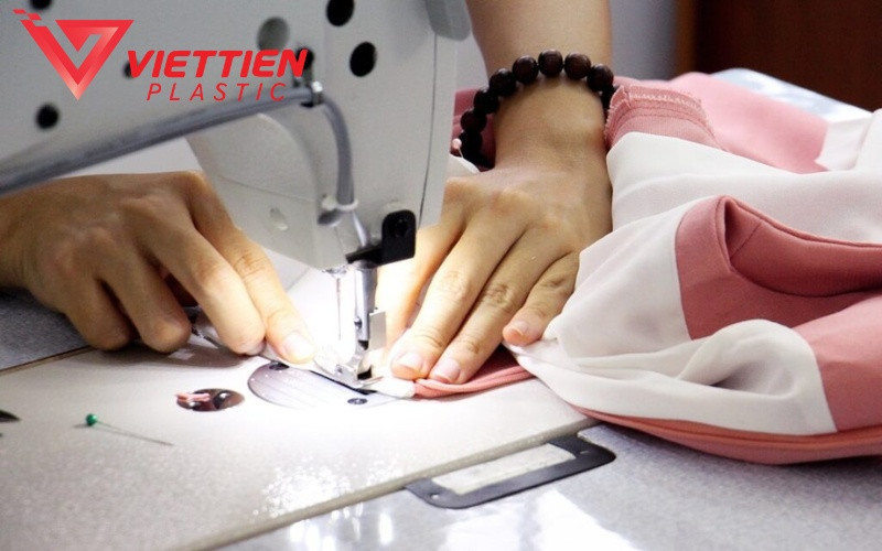 Người phụ nữ khéo léo vá lại quần áo cũ, tượng trưng cho việc tái chế và sửa chữa để kéo dài vòng đời sản phẩm thời trang.