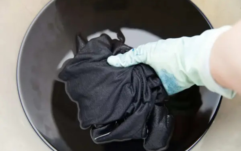 Quần áo đang được ngâm trong dung dịch thuốc nhuộm tự làm từ mực đen để đạt được màu đen sâu