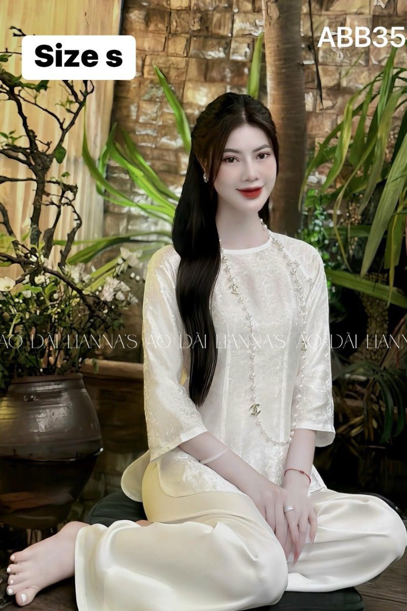 Set quần áo bà ba nữ tơ trắng kem, điểm xuyết hoa thêu hai tầng tinh xảo, mang lại vẻ đẹp quyến rũ và thanh lịch cho phái nữ